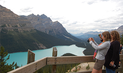 Two girls take photos of turqoise Peyto Lake below