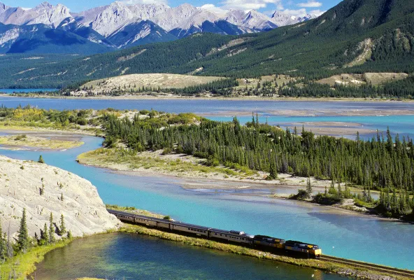 Via Rail train passing through the rockies, travelling alongside a turquoise-colored river
