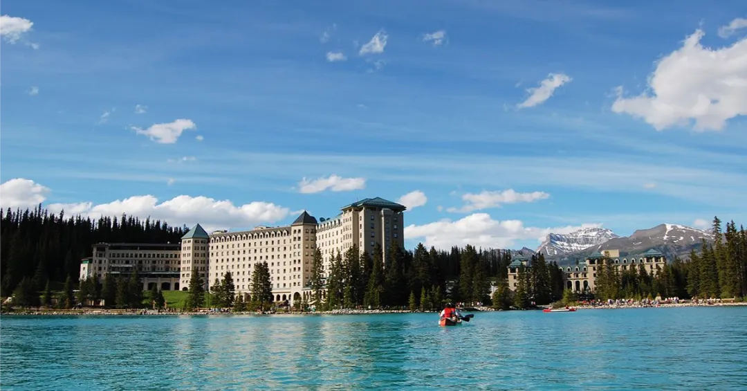 Couple canoeing on Lake Louise, overlooked by the Chateau