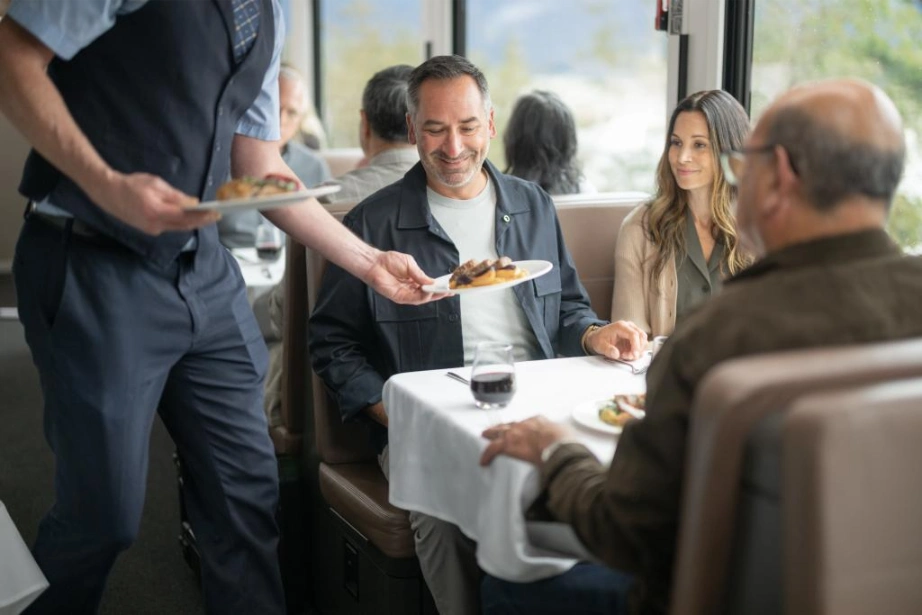A table being served a meal on the Rocky Mountaineer GoldLeaf dining car.